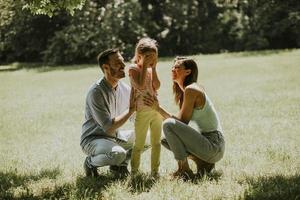 jeune famille heureuse avec une petite fille mignonne s'amusant dans le parc par une journée ensoleillée photo