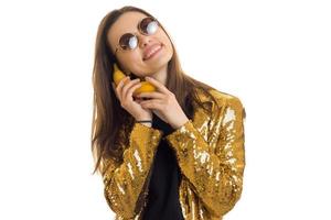 drôle de fille en lunettes de soleil rondes et veste dorée parlant avec la banane photo