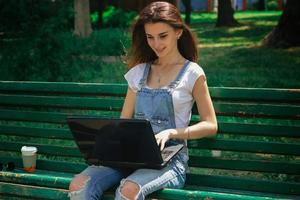 belles femmes assises avec un ordinateur portable sur le banc photo