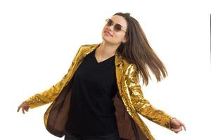 une jeune fille dans une veste lumineuse avec des paillettes et des lunettes de soleil posant en studio photo