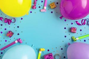cadre de fête coloré avec boîte-cadeau rouge avec divers confettis de fête, ballons, banderoles, pokers et décorations sur fond bleu. carte de vacances mise à plat vue de dessus joyeux anniversaire concept de fête photo