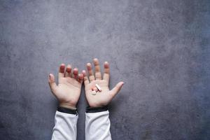 vue de dessus des pilules médicales sur la paume de la main de l'enfant sur fond noir photo