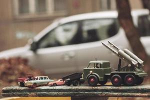 Petites voitures militaires soviétiques sur un banc dans la rue. photo