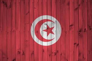 drapeau tunisien représenté dans des couleurs de peinture vives sur un vieux mur en bois. bannière texturée sur fond rugueux photo
