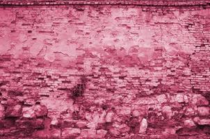 Très vieux mur de briques rouges endommagé avec des briques désossées et du mortier de ciment image tonique en viva magenta, couleur de l'année photo