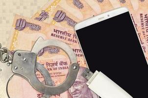 Billets de 10 roupies indiennes et smartphone avec menottes de police. concept d'attaques de phishing par des pirates, d'escroquerie illégale ou de distribution logicielle de logiciels malveillants photo