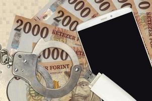 2000 factures de forint hongrois et smartphone avec menottes de police. concept d'attaques de phishing de pirates, d'escroquerie illégale ou de distribution logicielle de logiciels malveillants photo