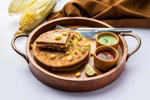paratha ou parotha farcis au maïs sucré servis dans une assiette, recette de pain plat indien faite de remplissage makai photo