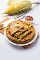 paratha ou parotha farcis au maïs sucré servis dans une assiette, recette de pain plat indien faite de remplissage makai photo