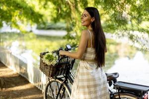 jeune femme avec des fleurs dans le panier de vélo électrique photo