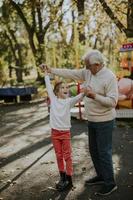 grand-père s'amusant avec sa petite-fille dans le parc d'attractions photo