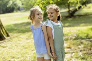 deux petites filles debout dos à dos dans le parc photo