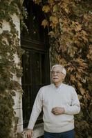 homme aîné, debout, par, fenêtre, à, les, automne, jour photo