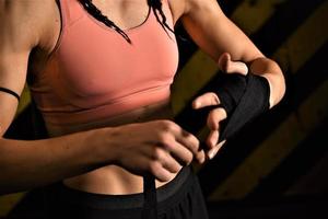 gros plan d'une femme faisant des bandages de boxe dans une cage de combat photo