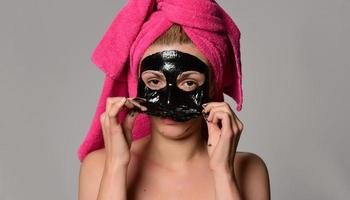 beau modèle féminin avec masque cosmétique facial noir. isolé sur fond gris photo