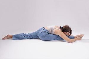 portrait d'une belle jeune femme avec un corps athlétique flexible faisant des étirements de jambe. isolée photo