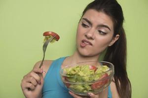 portrait d'une fille joyeuse et ludique mangeant de la salade fraîche dans un bol photo