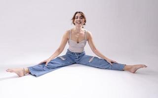 portrait d'une belle jeune femme avec un corps athlétique flexible faisant des étirements de jambe. isolée photo