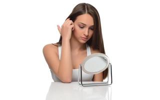 concept de peau sujette à l'acné. jeune femme regardant un miroir à la maison, vérifiant la peau de son visage photo