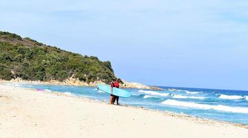 un homme est debout avec un surf dans ses mains sur le bord de la mer. photo