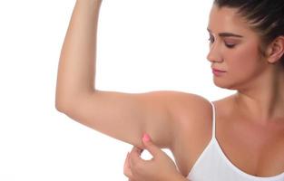 Femme pinçant une graisse sur ses bras sur fond blanc photo