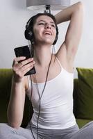 joyeuse jeune femme écoutant de la musique dans des écouteurs dans un appartement loft photo