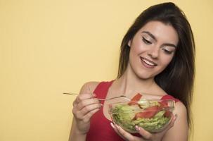 portrait d'une fille joyeuse et ludique mangeant de la salade fraîche dans un bol photo