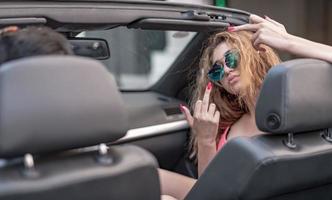 amis s'amusant lors d'un voyage en voiture autour du monde. couple amoureux avec les bras levés sur une voiture décapotable. photo