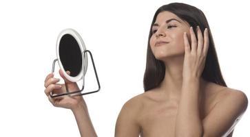 la femme touche la peau du visage regarde le miroir se sentant inquiète des premières rides et des changements liés à l'âge problèmes de derma. concept de soins de la peau de chirurgie plastique faciale cosmétique photo