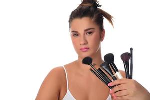 jeune fille posant avec des pinceaux de maquillage sur un fond blanc photo