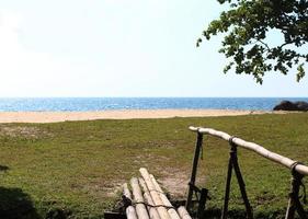 mer bleue et plage blanche, pont de bambou traversant la plage de sable photo