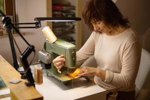 femme cousant du tissu avec une machine à coudre vintage et rétro. mode, création et confection. processus de couture en atelier ou en atelier. passe-temps particulier. photo