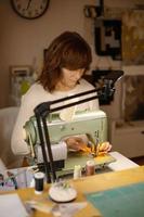 femme cousant du tissu avec une machine à coudre vintage et rétro. mode, création et confection. processus de couture en atelier ou en atelier. passe-temps particulier. photo