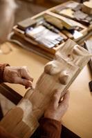 l'artiste broie une sculpture en bois. charpentier travaillant le bois en atelier. l'homme et son passe-temps. vue rapprochée, seules les mains dans le cadre. photo