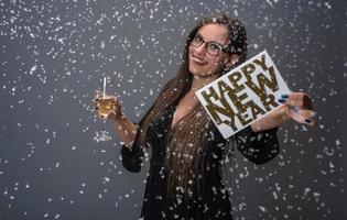 belle femme célébrant le nouvel an avec des confettis et du champagne tenant une pancarte. isolée photo