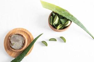 tranches d'aloe vera frais et tranches d'une plante juteuse dans des bols en bois sur fond blanc texturé. vue de dessus. hydratant, rajeunissant la peau. photo