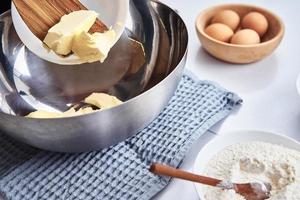 les mains mettent du beurre dans un bol. recette de cuisine photo