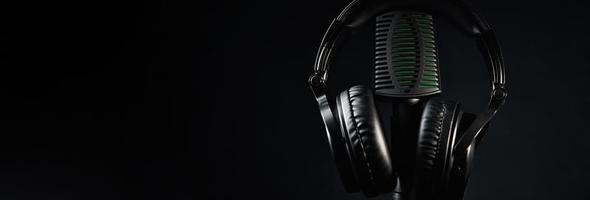 microphone de studio et casque sur fond noir. concept de podcast en ligne photo