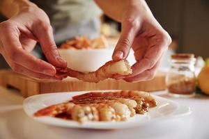 femme prend des crevettes crues fraîches dans une assiette. cuisson des crevettes photo