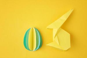 lapin en papier origami esater et oeuf coloré sur fond jaune photo