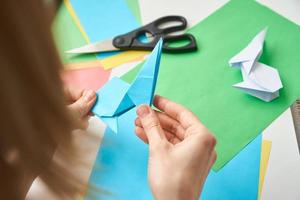 notion de bricolage. femme fait un lapin de pâques origami à partir de papier de couleur. cours d'origami photo