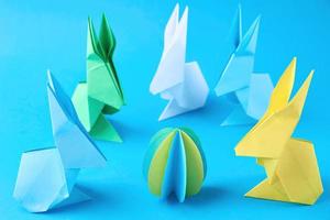 lapins en papier origami esater et oeufs colorés sur fond bleu photo