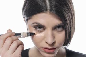 portrait d'une jeune femme appliquant un maquillage liquide sur son visage. isolé sur fond blanc photo