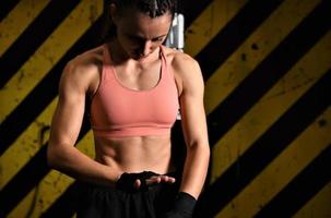 gros plan d'une femme faisant des bandages de boxe dans une cage de combat photo