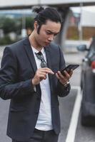 un bel homme asiatique utilisant un téléphone intelligent dans la ville photo