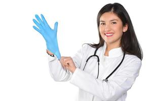 Une jeune femme médecin avec stéthoscope mettant un gants médicaux, isolé sur fond blanc photo