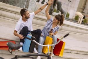 portrait d'un jeune couple caucasien joyeux homme et femme tenant de nombreux sacs en papier après avoir fait du shopping en marchant et en parlant dans la rue. couple de famille heureux avec forfaits en plein air. notion d'achat photo