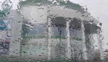 gouttes de pluie sur le fond de la vitre de la voiture, la vue de la voiture au centre commercial par mauvais temps. photo