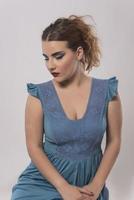 Belle femme en robe bleue qui pose en studio sur fond gris photo