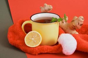 bonnet de noel, tasse de rea, racine de gingembre, feuilles de menthe et citrons sur fond rouge photo